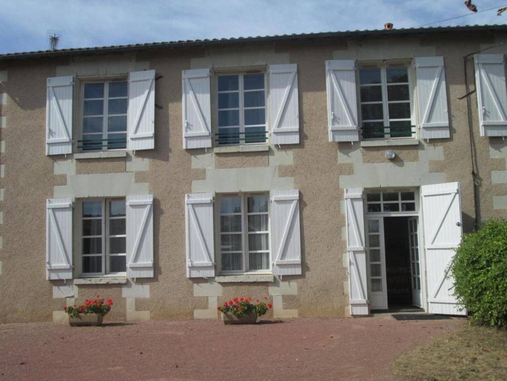 una casa con ventanas blancas y flores delante de ella en Le marronnier, en Saint-Jean-de-Sauves