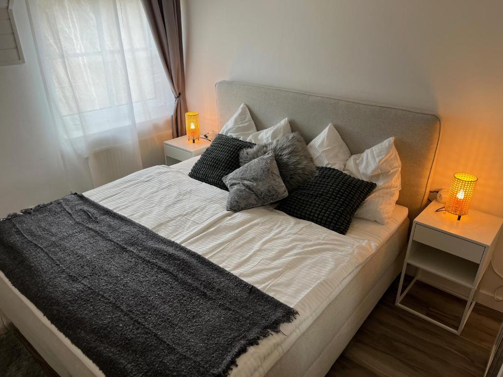 1 cama con almohadas blancas y negras y ventana en Seebrise Velden - only 500 meter from lake!, en Velden am Wörthersee