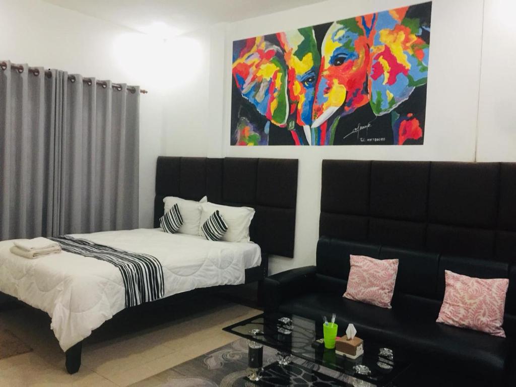 um quarto com uma cama, um sofá e um quadro em EZ Guesthouse em Phnom Penh