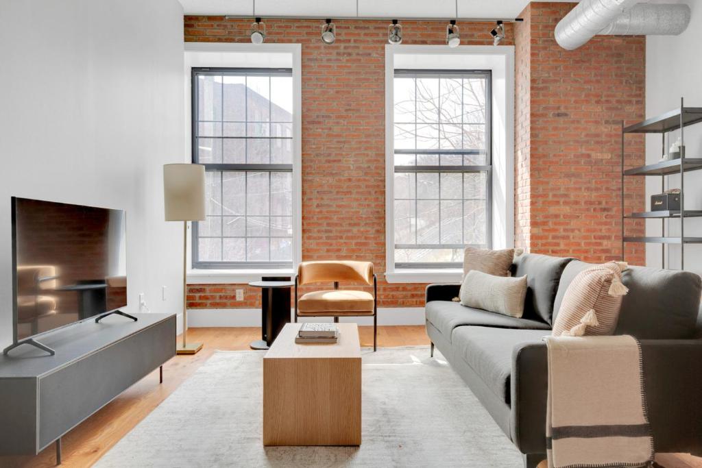 ein Wohnzimmer mit Sofa und Ziegelwand in der Unterkunft Jersey City 2BR w WD DM free shuttle to PATH NYC-761 in Hoboken