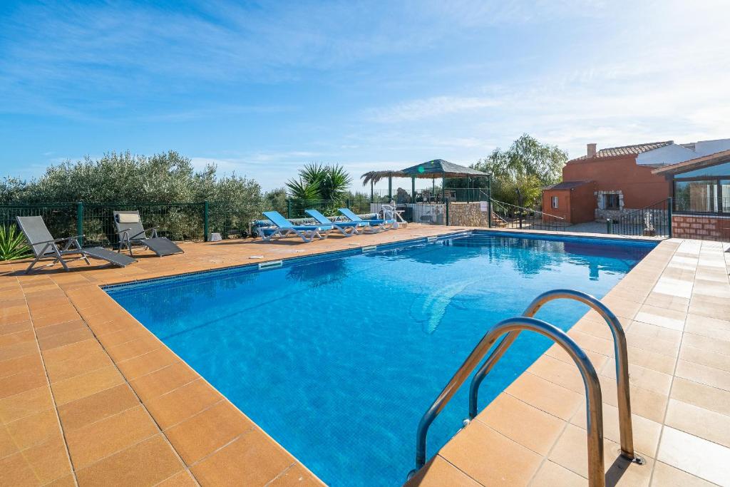a large swimming pool with chairs and a gazebo at Hauzify I Mas Bomba in Les tres Cales