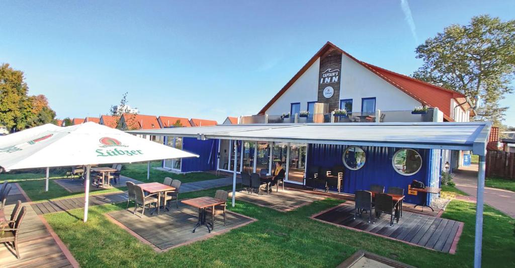 a building with a patio with tables and an umbrella at Kuhnle-Tours Ferienwohnung in Rechlin