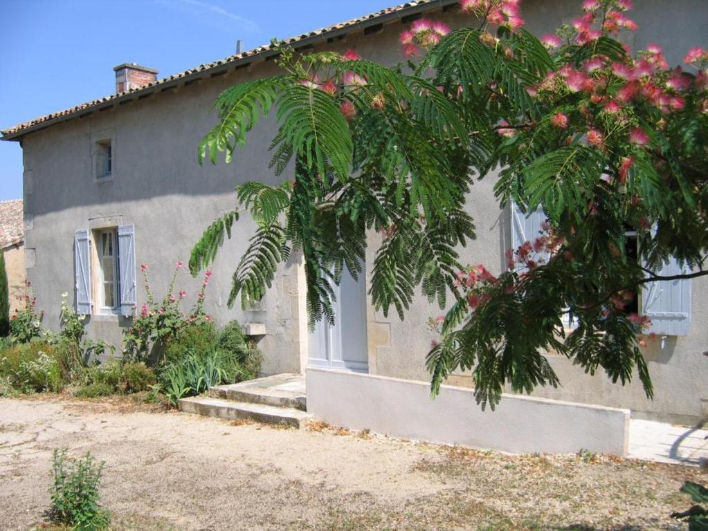 a house with a tree with pink flowers in front of it at Gîte robale in Romagne