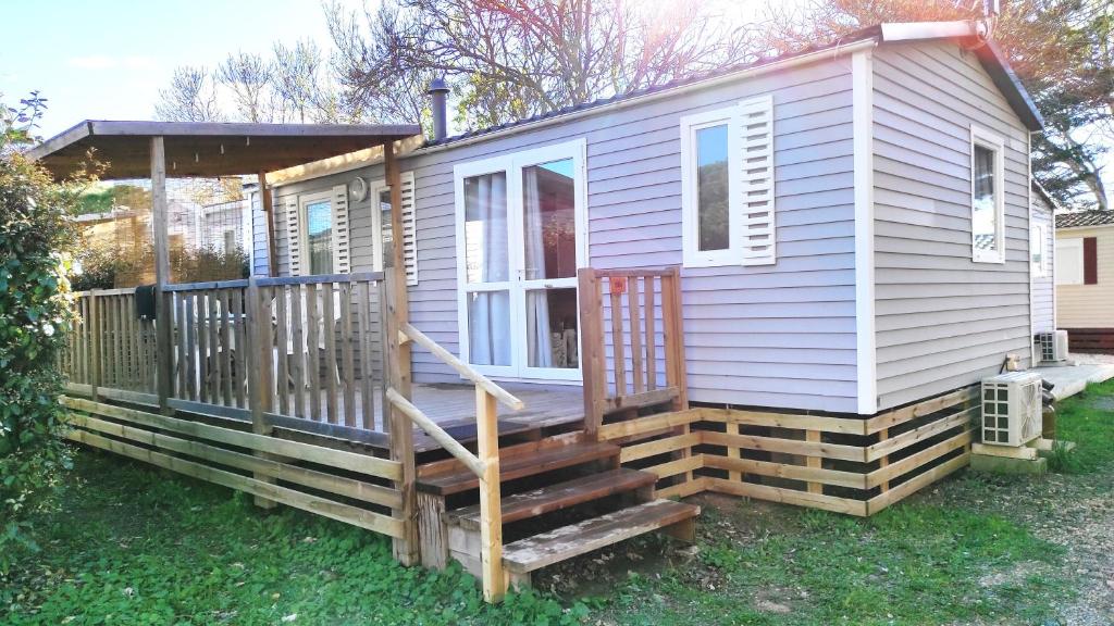 ein winziges Haus mit einer Veranda und einer Treppe in der Unterkunft Mobil home 6 personnes PORT LA NOUVELLE in Port-la-Nouvelle