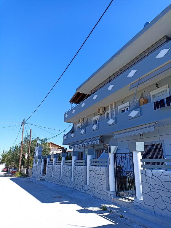a blue building with a fence in front of it at Seven Seas Apartments in Artemida