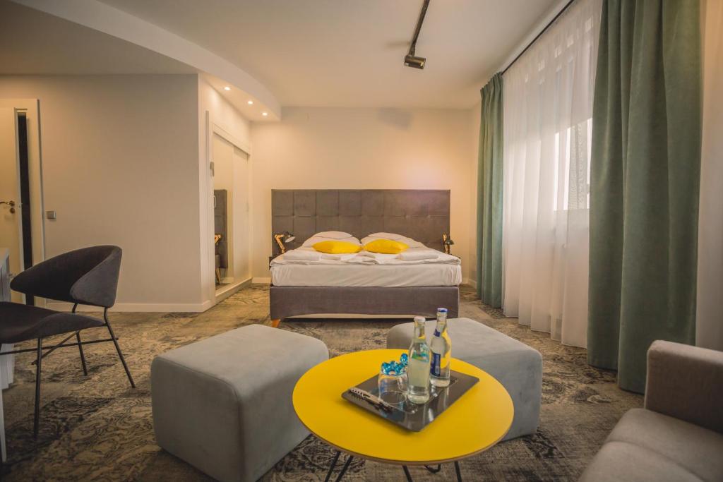 クロスノにあるHotel Nafta Krosnoのベッドと黄色のテーブルが備わるホテルルームです。