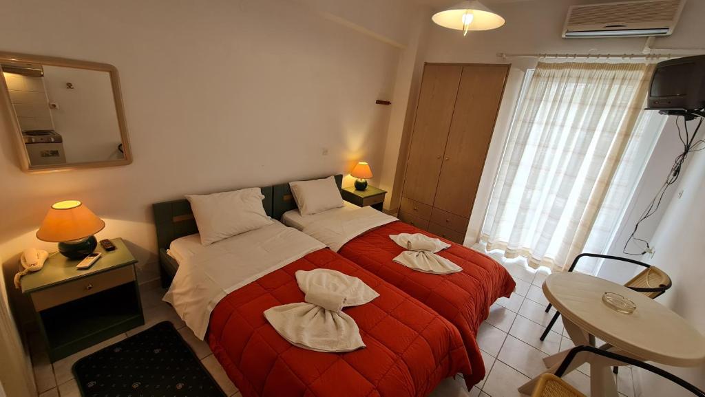a bedroom with two beds and a red blanket at Kapolos budget hotel in Loutra Edipsou