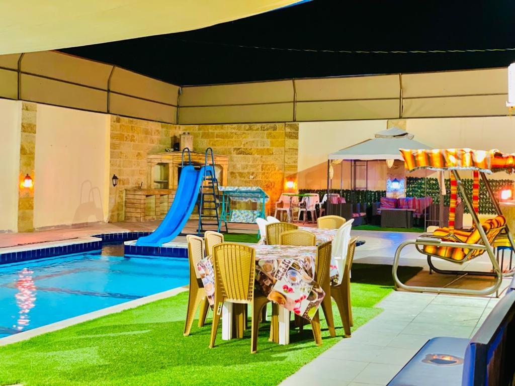 a patio with a table and chairs next to a pool at SARA HOME 2 in Al Kafrayn