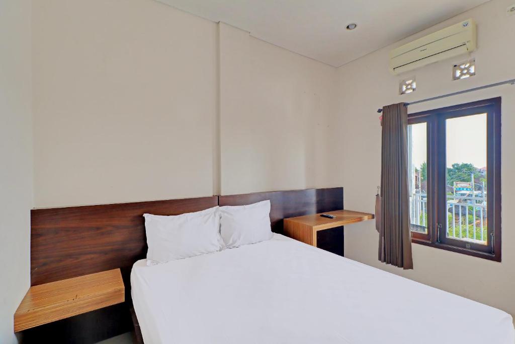 a bedroom with a large bed and a window at OYO 92315 Prostay Bali in Denpasar