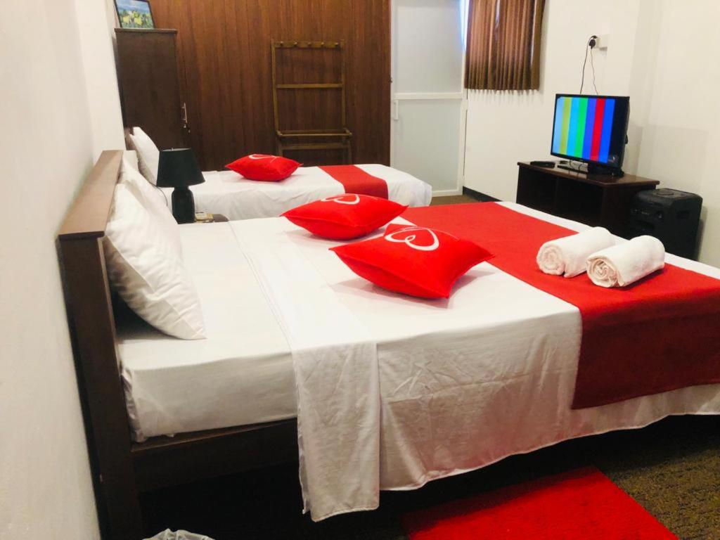 2 Betten mit roten Kissen und TV in einem Zimmer in der Unterkunft Cannel view apartment Negombo in Negombo