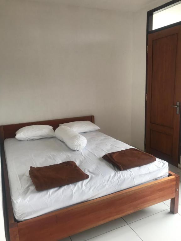 uma cama com lençóis brancos e almofadas num quarto em Makini Guest House em Lambangkuning