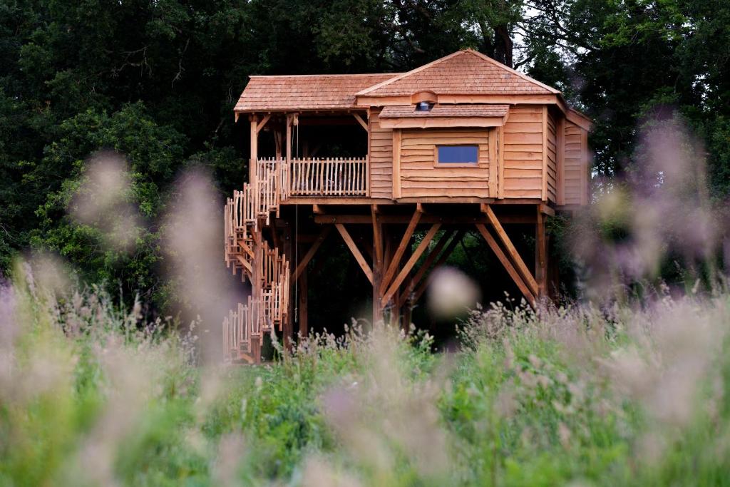 a wooden tree house with a deck in a field at Dihan Evasion in Ploemel
