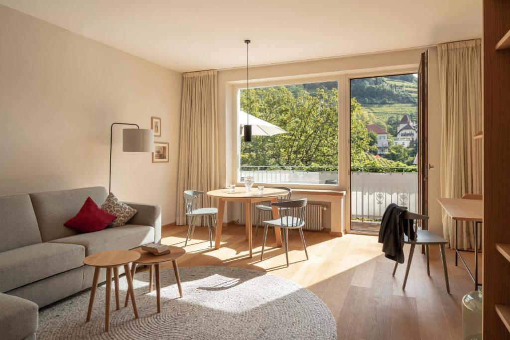 un soggiorno con divano e tavolo con sedie di Der Ladurner Hof - Wohnen am Weinberg a Merano