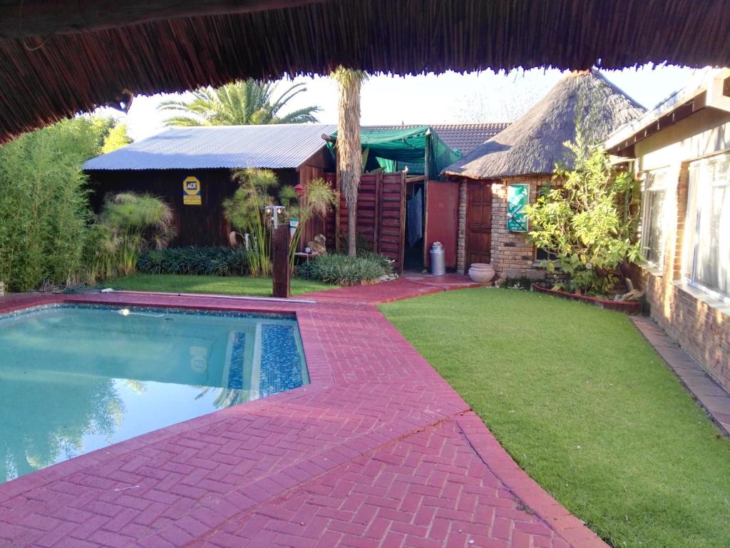 a backyard with a swimming pool and a house at Ay Jay's Guesthouse in Bloemfontein