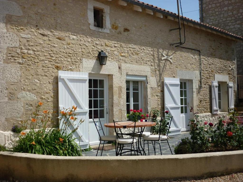 een patio met een tafel en stoelen voor een gebouw bij Le gite du porche in Saint-Georges-lès-Baillargeaux