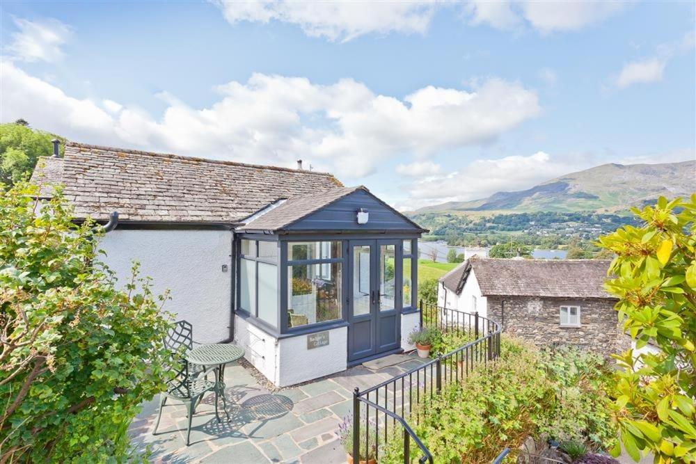a cottage with a patio with a table and a chair at Badger's Cottage with stunning lake & mountain views in Coniston