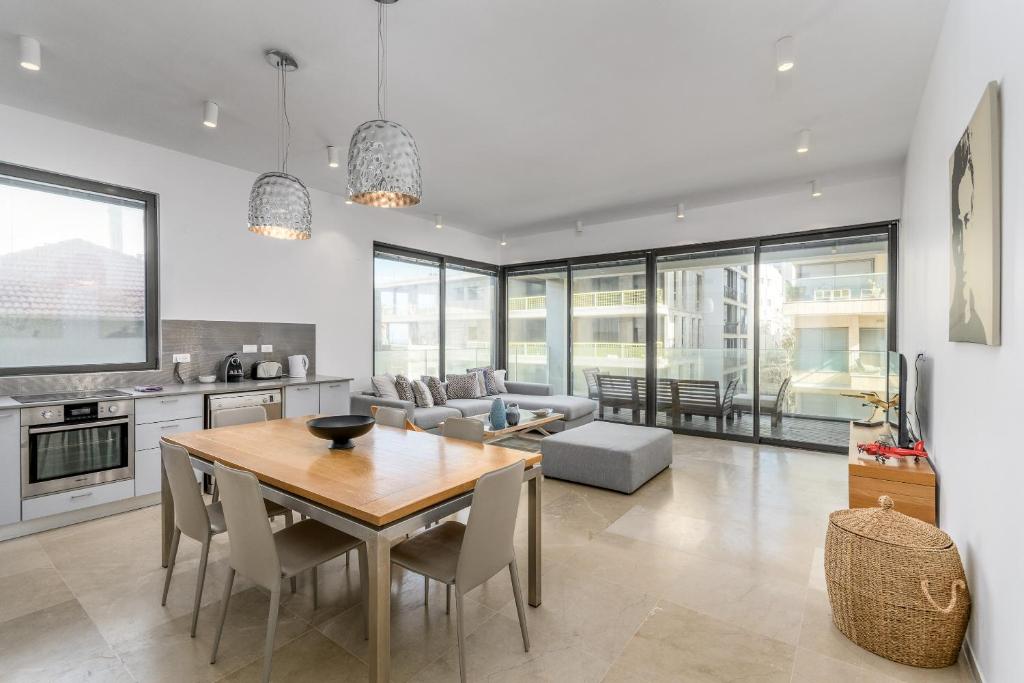 a kitchen and living room with a wooden table and chairs at Luxury 3BR on Frishman SEA u TLV in Tel Aviv