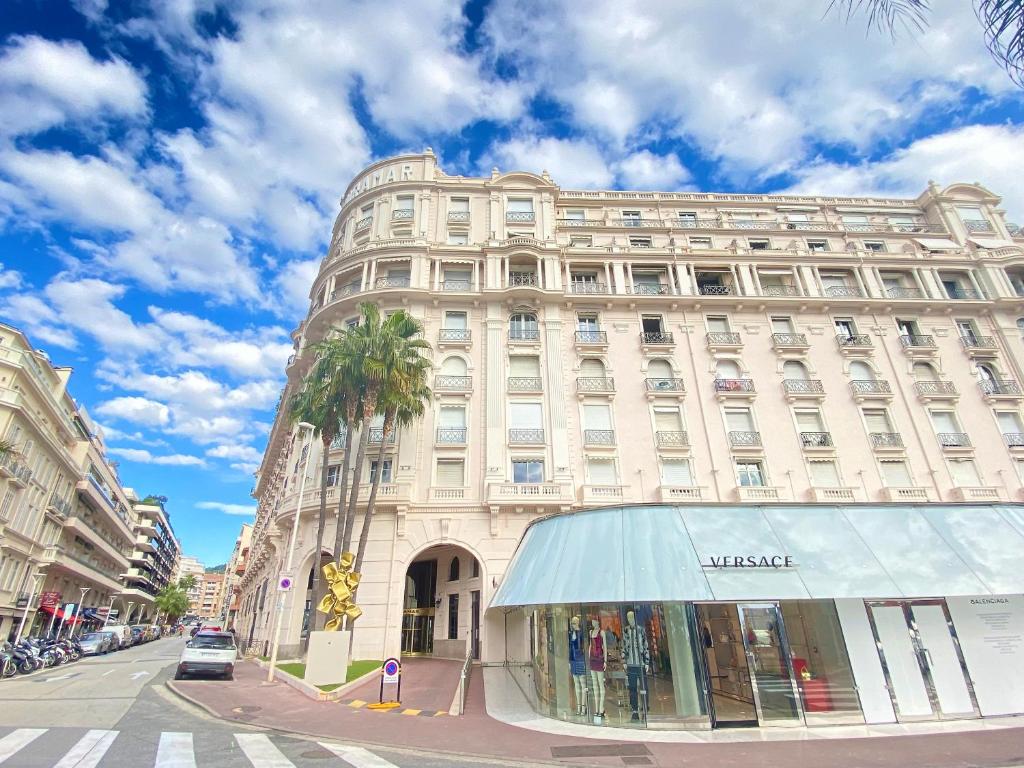 un grand bâtiment blanc avec un palmier en face dans l'établissement Croisette Beach & Palace, à Cannes