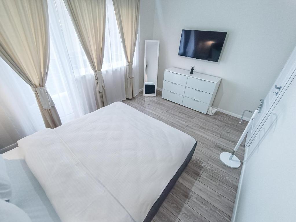 TEILOR Apartments 3 في فلورستي: غرفة نوم بيضاء مع سرير وتلفزيون