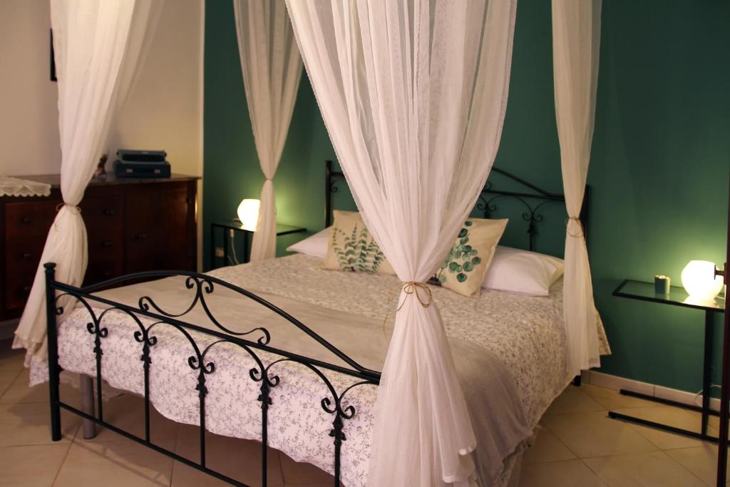 a bedroom with a canopy bed with white curtains at Tenuta Piana 2 con accesso diretto al mare in Caronia