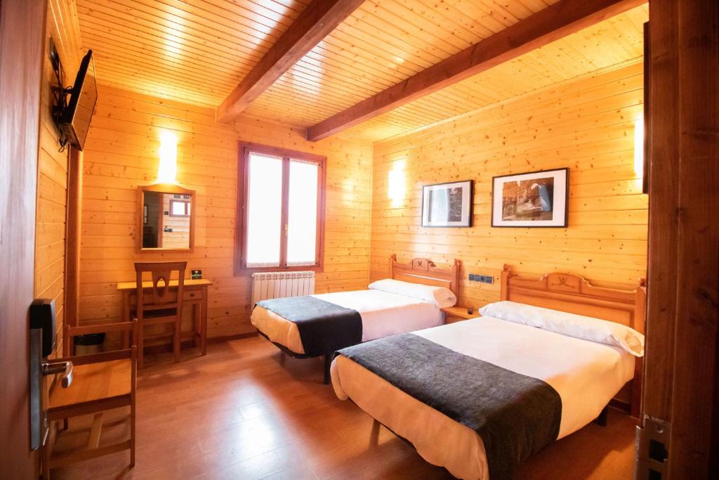 a bedroom with two beds and a desk and a table at Alda Palas de Rei in Palas de Rei