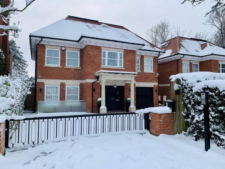 a brick house with a fence in the snow at Luxury detached 4-bedroom villa with free parking in Cockfosters