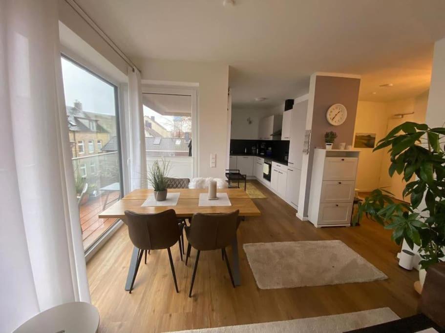 a living room with a table and chairs and a kitchen at Moderne Penthouse Wohnung in Schleswig