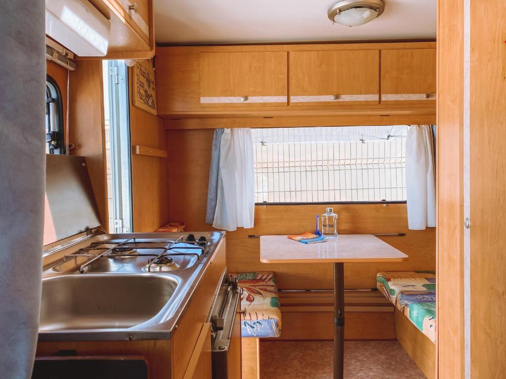 uma cozinha com um lavatório, um fogão e uma mesa em Glamping Caravan Lanzarote em Tinajo