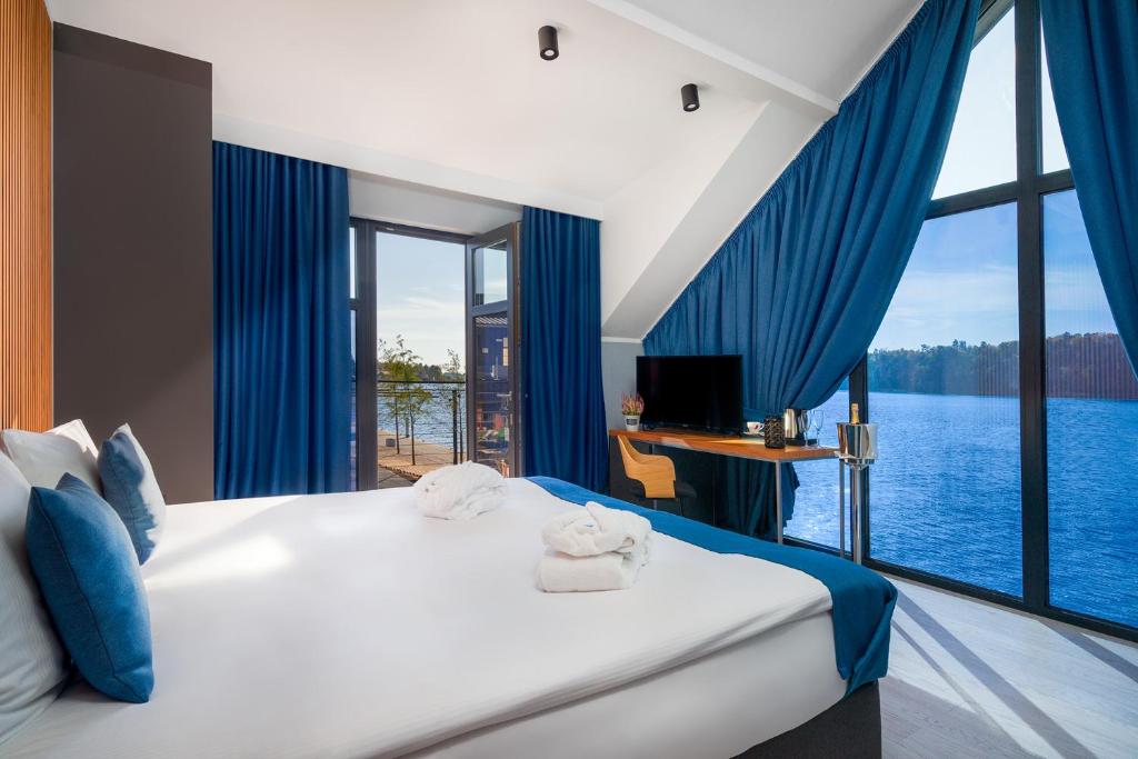 sypialnia z dużym łóżkiem z niebieskimi zasłonami i dużym oknem w obiekcie Kurort Kameralny w mieście Mikołajki