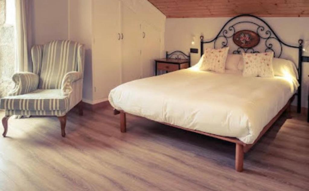 een slaapkamer met een groot bed en een stoel bij O Lagoeiro in A Estrada