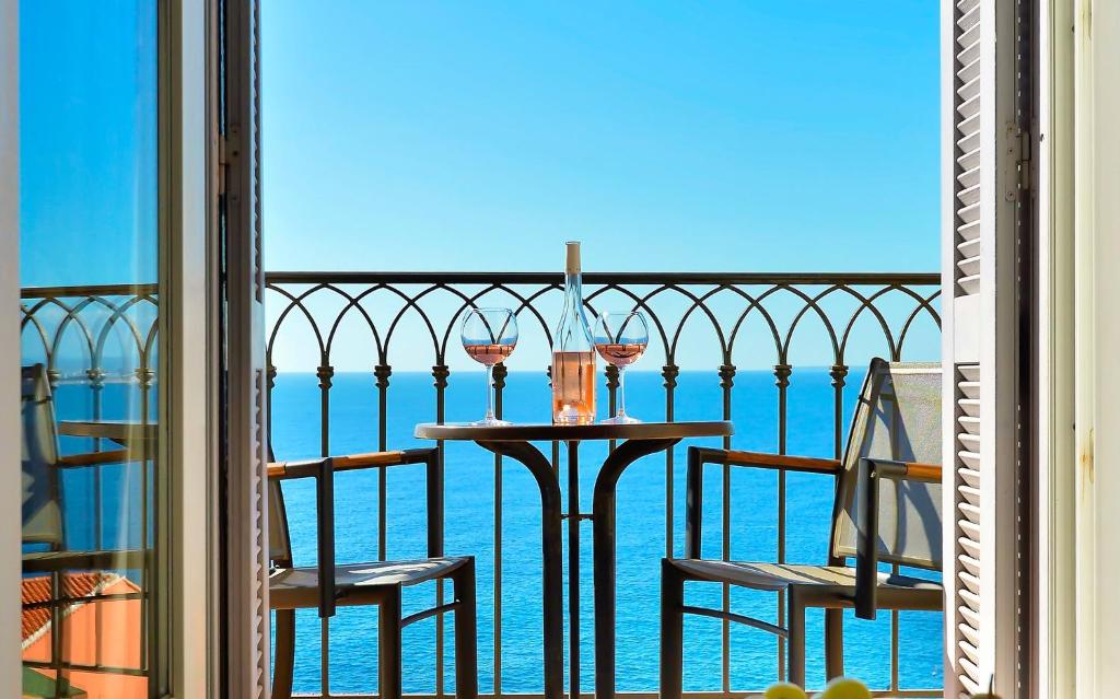 a table with two glasses of wine on a balcony at Hôtel La Pérouse Nice Baie des Anges - Recently fully renovated in Nice