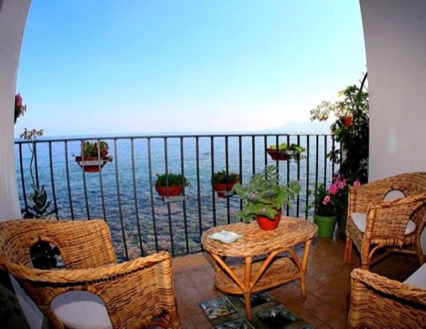 einen Balkon mit einem Tisch, Stühlen und Meerblick in der Unterkunft B&B La Veduta in Scilla