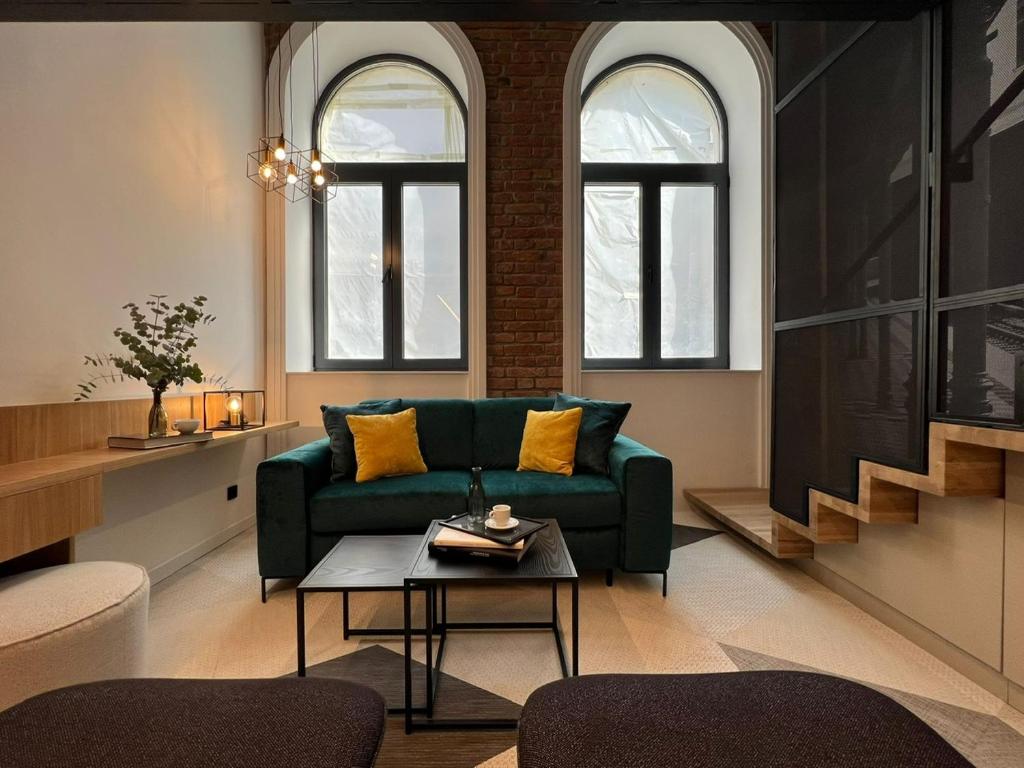 ein Wohnzimmer mit einem grünen Sofa und 2 Fenstern in der Unterkunft Fesh Lofts in Wien