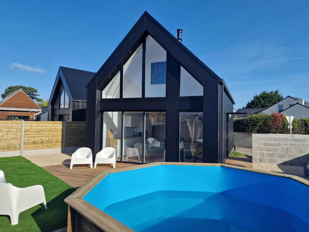 une maison avec une piscine en face de celle-ci dans l'établissement LES PORTSALLAISES piscine ou spa à 300m de la plage, à Ploudalmézeau