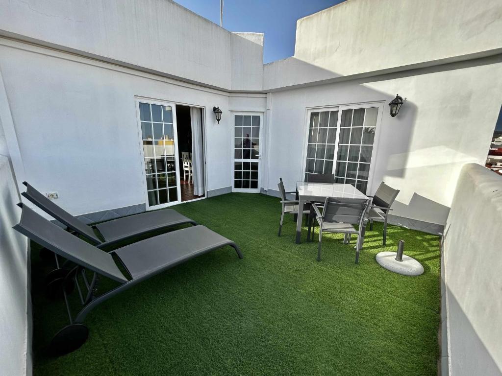 a patio with a table and chairs and grass at Atico eloy delgado in San Miguel de Abona
