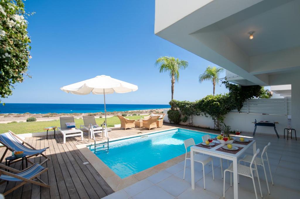 a villa with a swimming pool and the ocean at Jasmine Sea Front Villa in Protaras