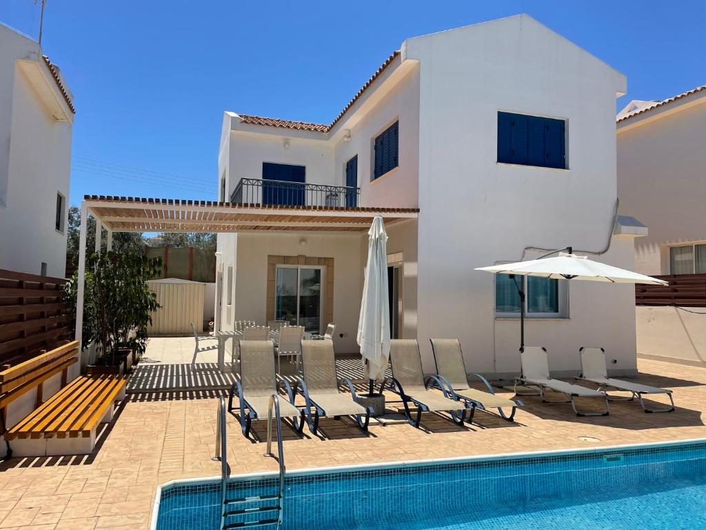 a villa with a swimming pool with chairs and umbrellas at Sol y Mar Malama Villa in Paralimni