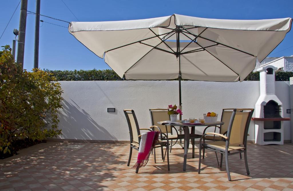 un tavolo e sedie sotto un ombrellone su un patio di Acquamarina di Mancaversa a Marina di Mancaversa