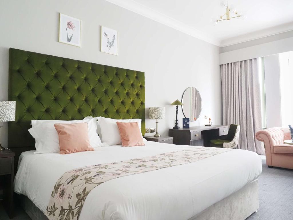 een slaapkamer met een groot bed met een groen hoofdeinde bij Hotel Collingwood BW Signature Collection in Bournemouth