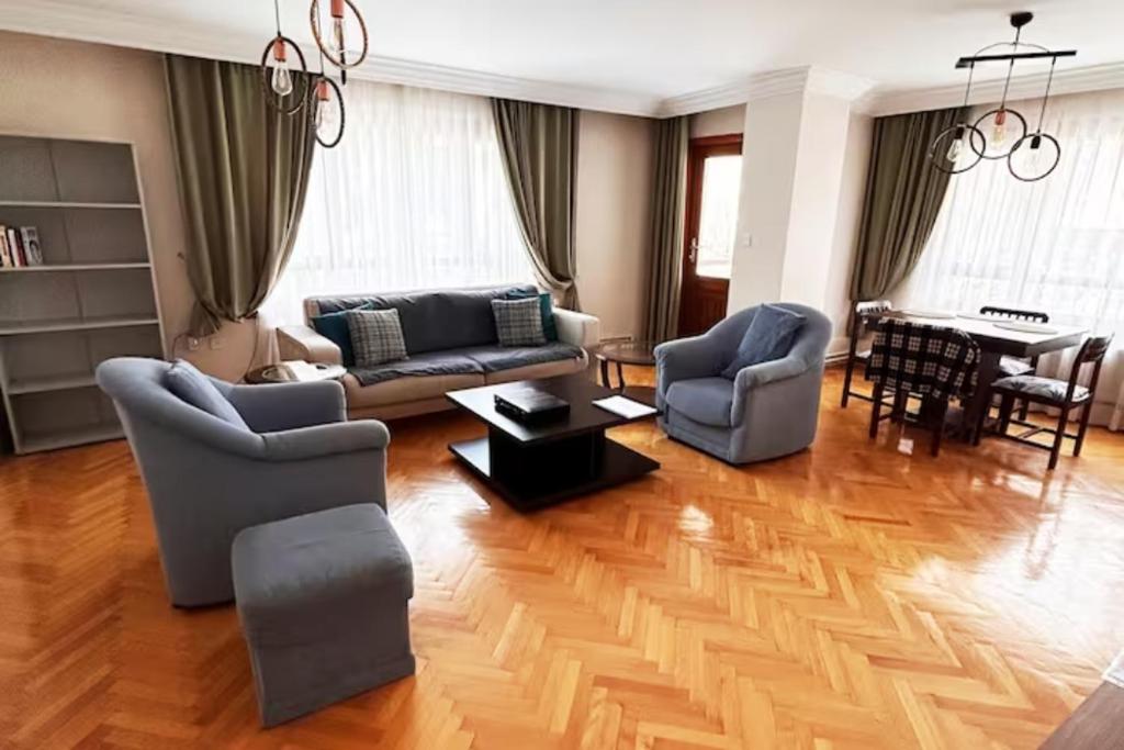 A large, comfortable flat in the best area of Ankara, Turkey في أنقرة: غرفة معيشة مع أريكة وكراسي وبيانو