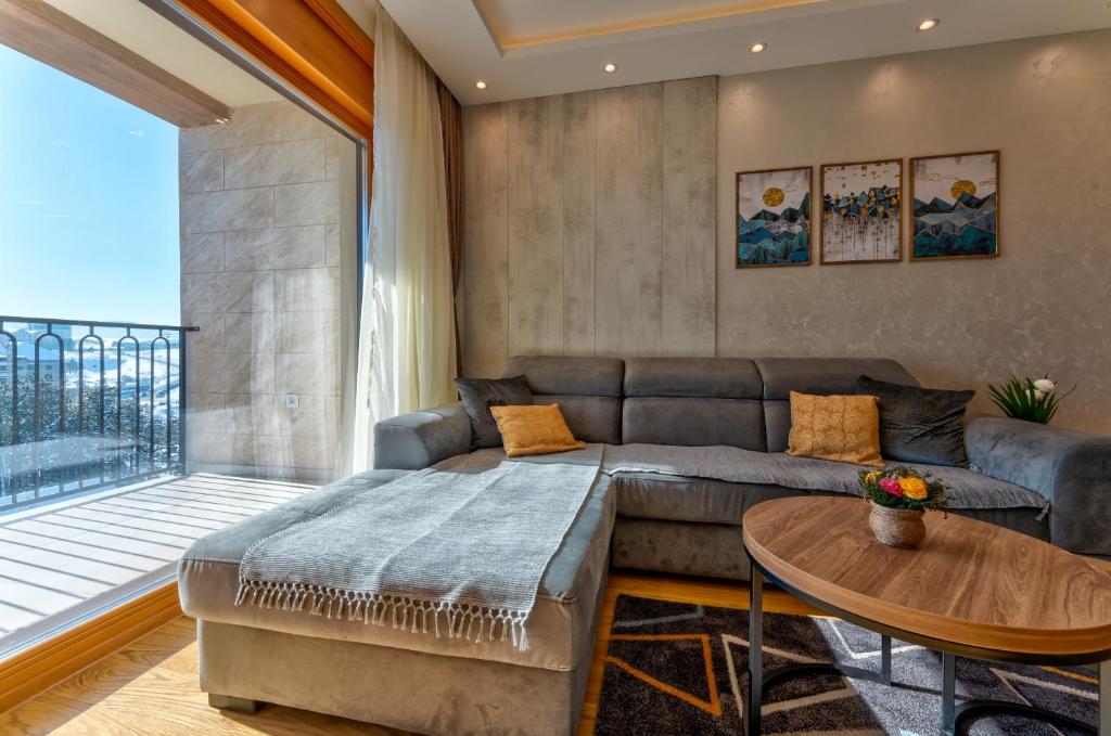 - un salon avec un canapé et une grande fenêtre dans l'établissement Zlatibor apartmani Kika, à Zlatibor