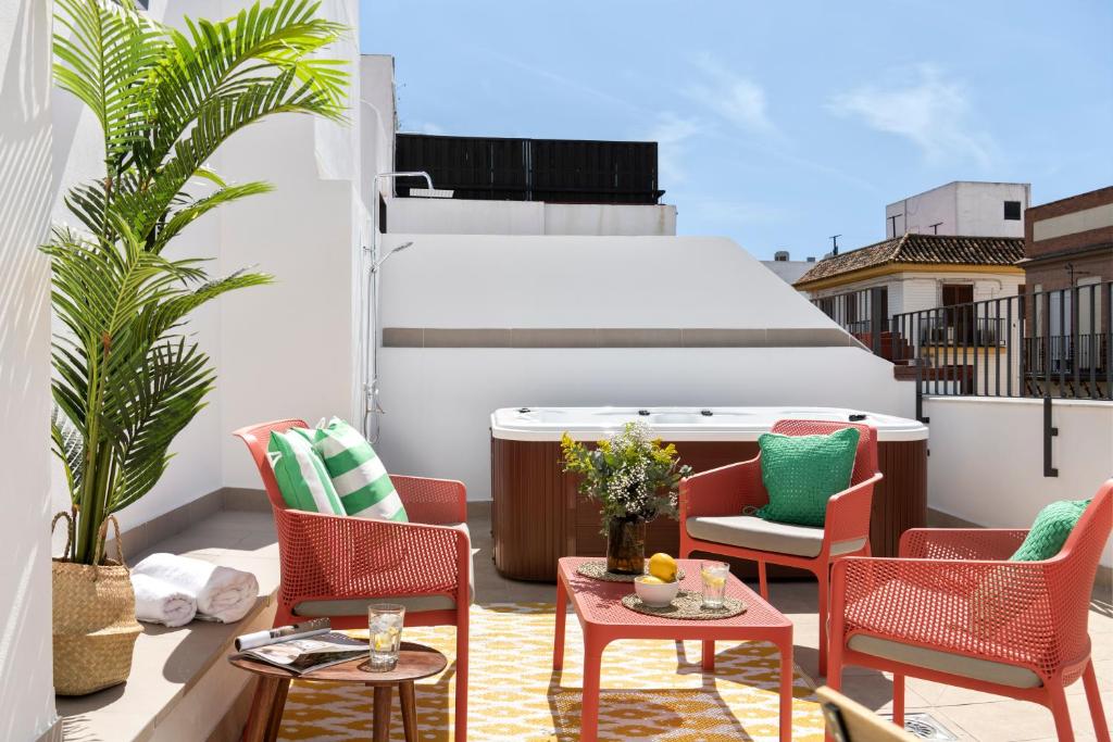 un patio con sillas y mesas en un balcón en Magno Apartments Feria 132 en Sevilla
