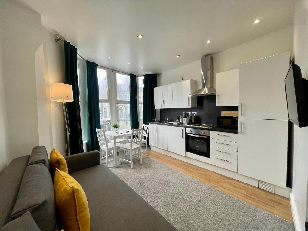 a living room with a couch and a kitchen at Stylish Modern Apartment For Up To 4 Nr CityCentre in Cardiff