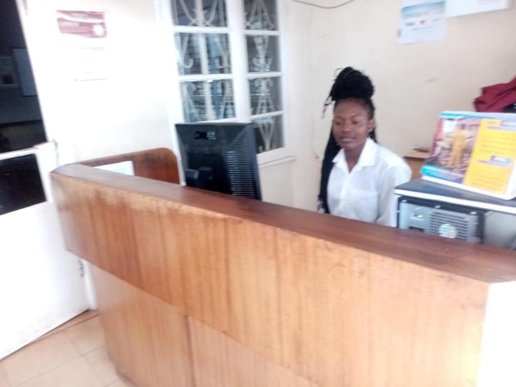 a woman standing behind a counter in a office at Melvic Hotel in Kisumu