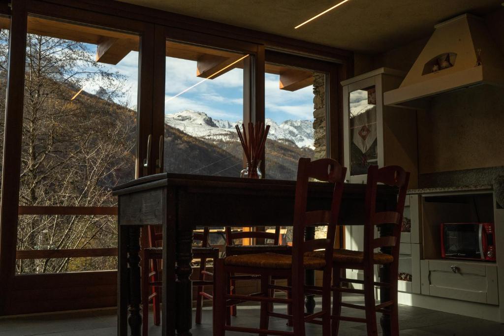 a dining room with a view of the mountains through a window at AMELU' LOCAZIONI TURISTICHE in Ostana
