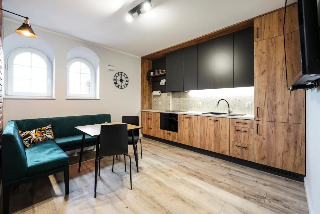 a kitchen with black cabinets and a table and a green couch at Młyn Wrocław 10/8 in Wrocław