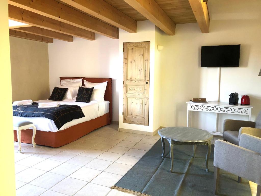 a bedroom with a bed and a table and a tv at Une chapelle en soie in Taulignan