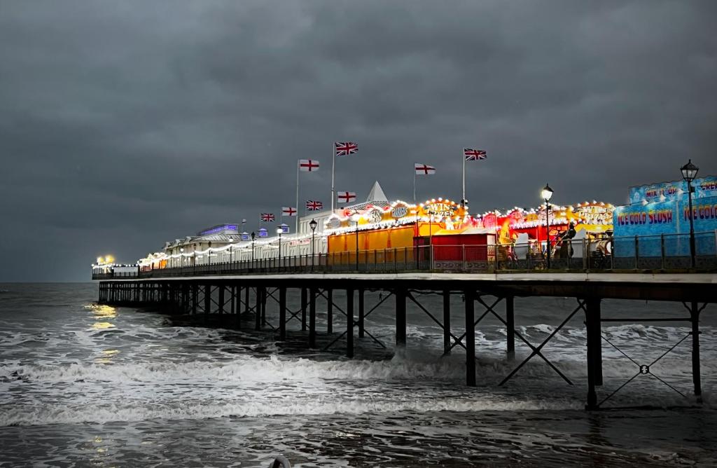 a pier with lights on the water at night at The Commodore Rooms & Relaxation in Paignton