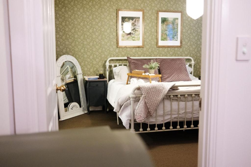 um quarto com uma cama e um espelho em Enchanting Retreat - The English Cottage at Tamborine Mountain em Mount Tamborine