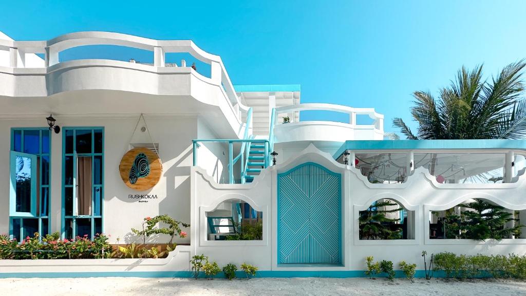 una casa blanca con una puerta azul delante en Rushkokaa Beach Villa, en Fulidhoo